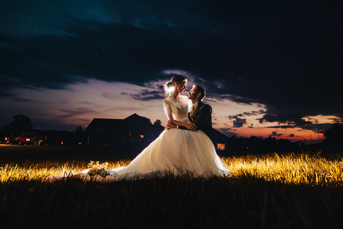 Romantisches Brautpaar bei Sonnenuntergang – Hochzeitsfoto im Abendlicht auf einer Wiese