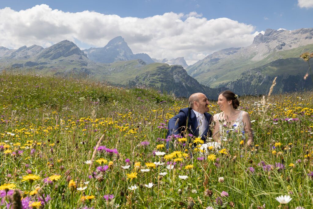 Hochzeitspaar auf einer farbenfrohen Alpwiese vor beeindruckender Bergkulisse