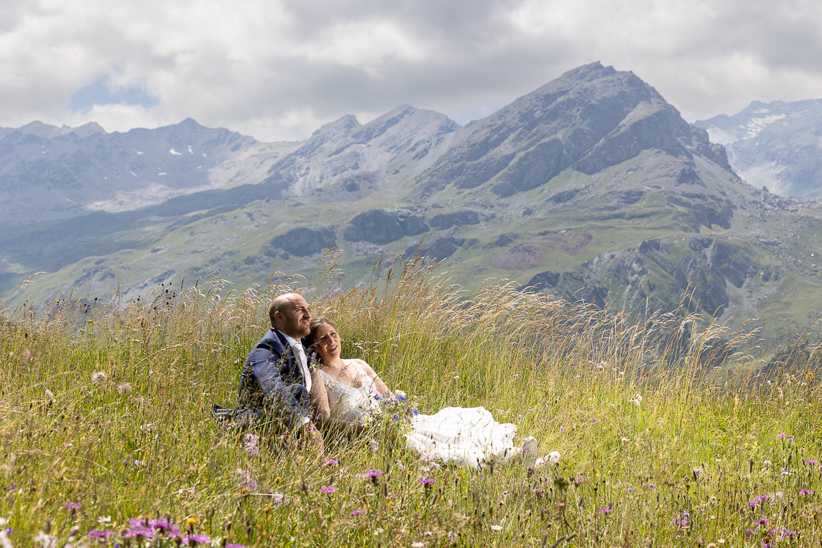 Romantisches Brautpaar im Bergblumenfeld auf der Alp Flix, eingefangen von Hochzeitsfotograf Adrian Flütsch.