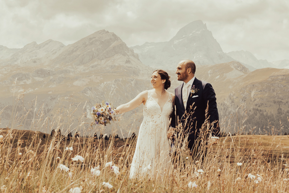 Brautpaar auf der Alp Flix mit atemberaubender Bergkulisse, aufgenommen während einer Hochzeit von Hochzeitsfotograf Adrian Flütsch.