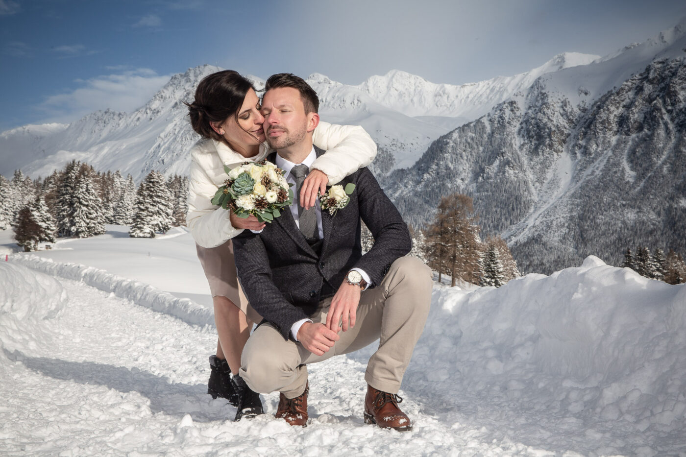 Hochzeitspaar auf einem Winterwanderweg in den Schweizer Bergen