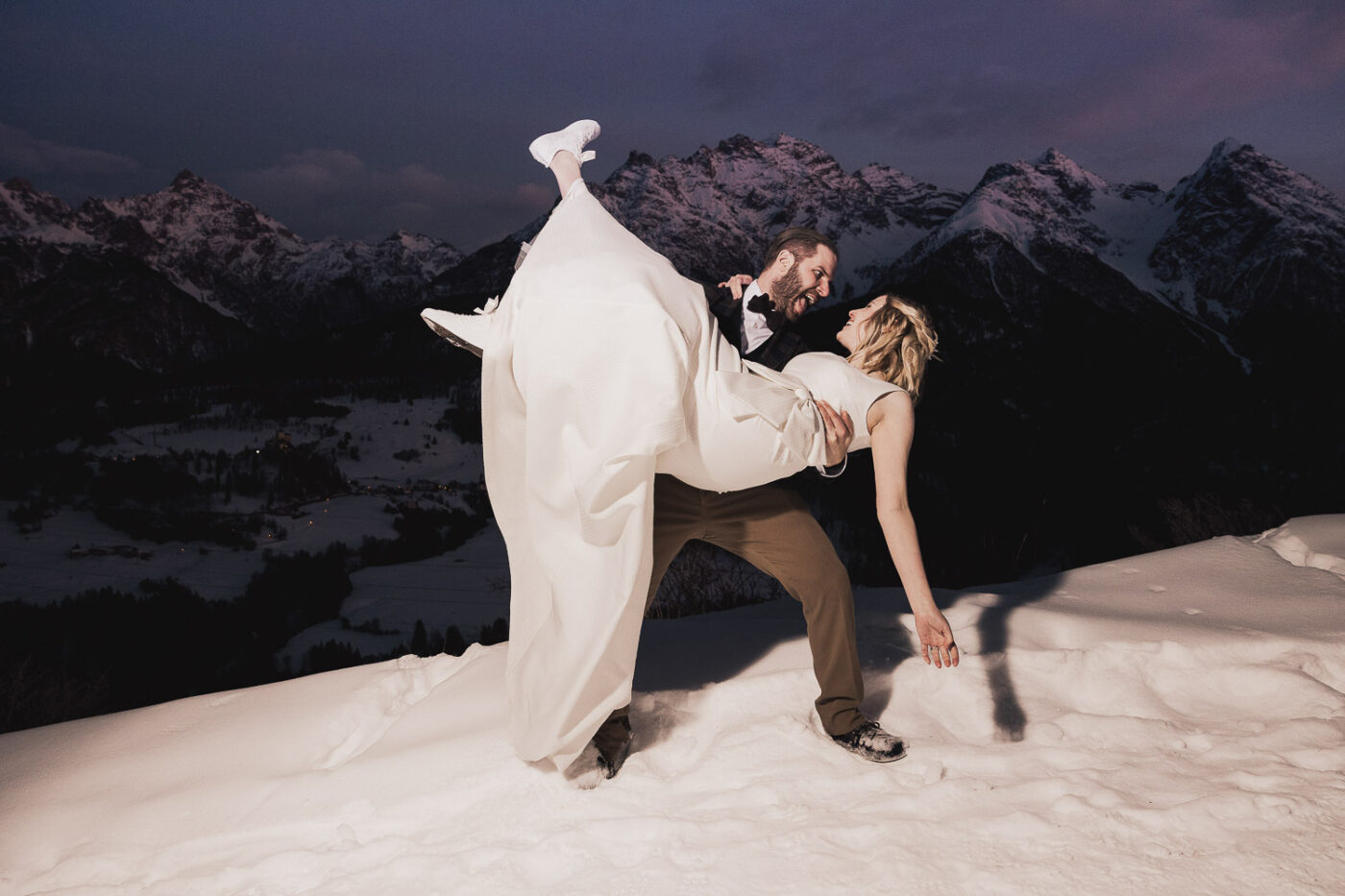 Hochzeitspaar in den verschneiten Alpen bei Sonnenuntergang - zauberhaftes Fotoshooting im Schnee