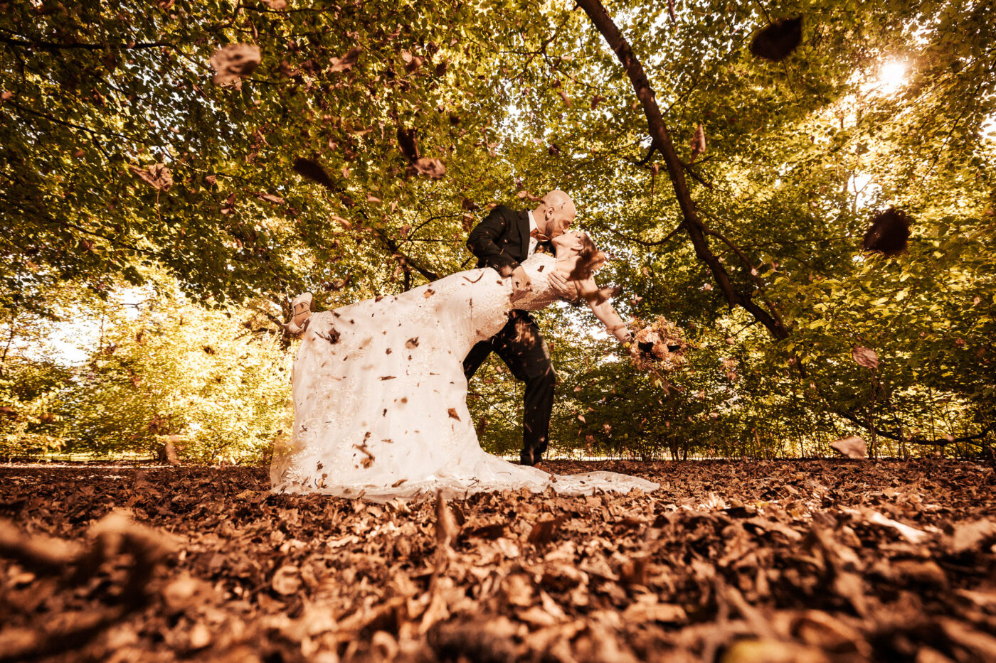 Hochzeitspaar im herbstlichen Blätterregen