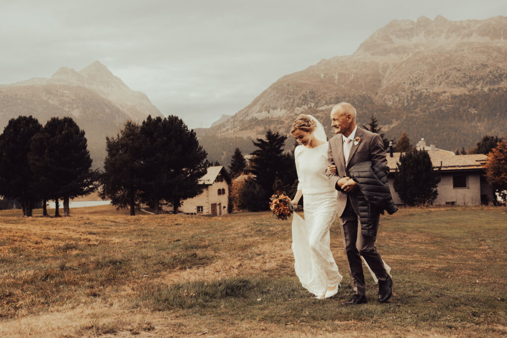 Braut mit ihrem Vater auf dem Weg zur Trauung im Engadin, festgehalten von Hochzeitsfotograf Adrian Flütsch.