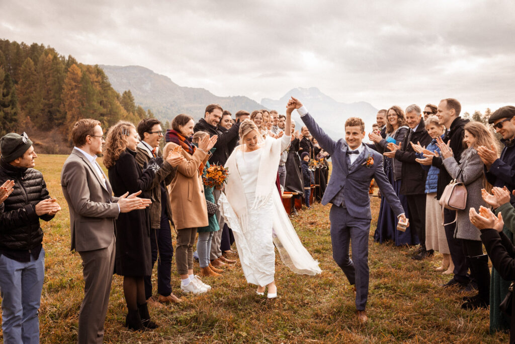 Brautpaar Deborah und Patrick bei ihrem Auszug nach der Trauung im Engadin, festgehalten von dem renommierten Hochzeitsfotografen Adrian Flütsch.