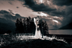 Dramatisches Hochzeitsfoto von Deborah und Patrick vor einer dunklen Wolkenkulisse im Engadin, festgehalten vom renommierten Hochzeitsfotografen Adrian Flütsch.