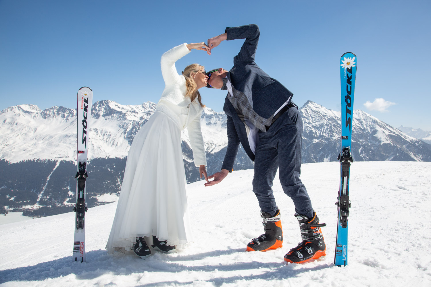 Brautpaar formt ein Herz mit den Händen auf der Skipiste im Skigebiet Lenzerheide