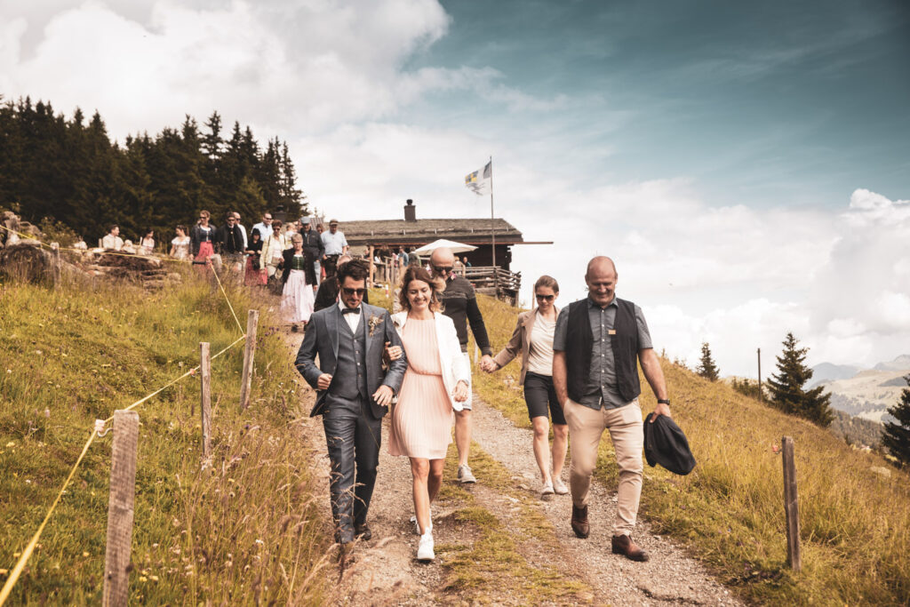 Hochzeitsgesellschaft bei einer malerischen Alphochzeit in Lenzerheide, festgehalten vom bekannten Hochzeitsfotografen Adrian Flütsch.