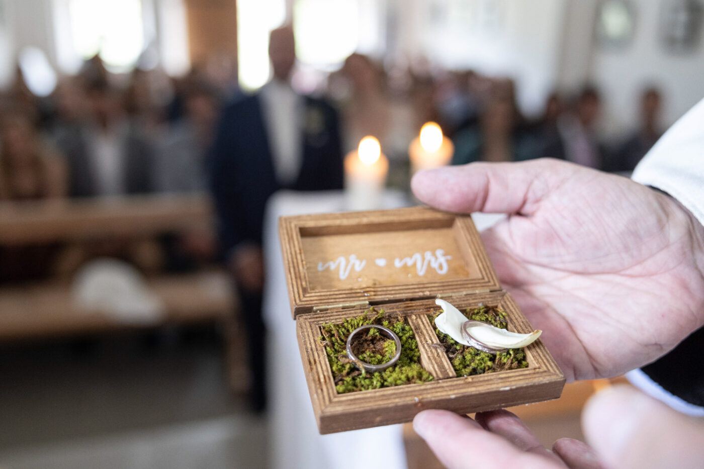 Eheringe in einer rustikalen Holzbox während einer Hochzeit auf der Alp Flix, fotografiert von Hochzeitsfotograf Adrian Flütsch.