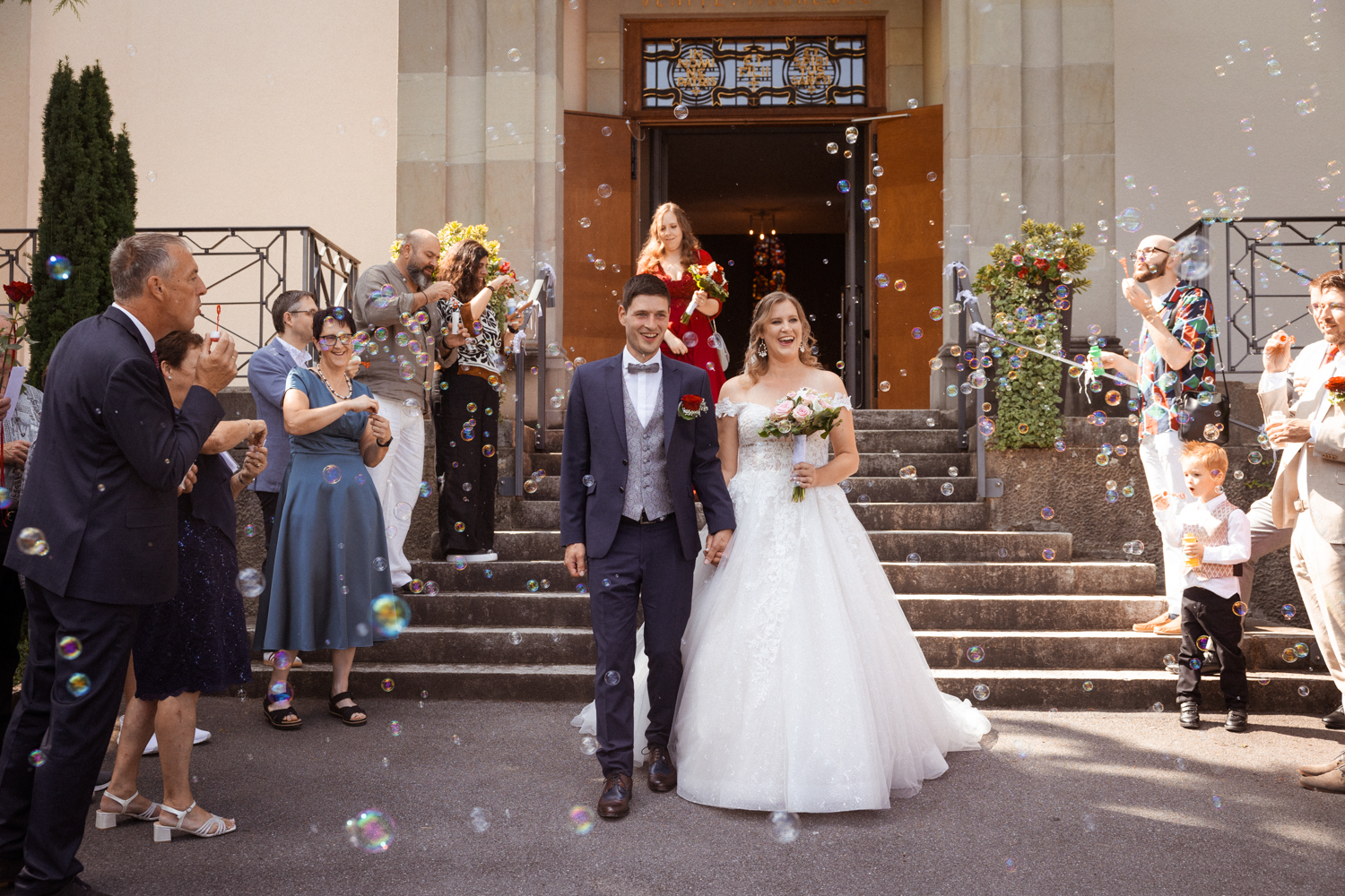 Hochzeitspaar vor der Kirche in Unterterzen mit jubelnden Gästen