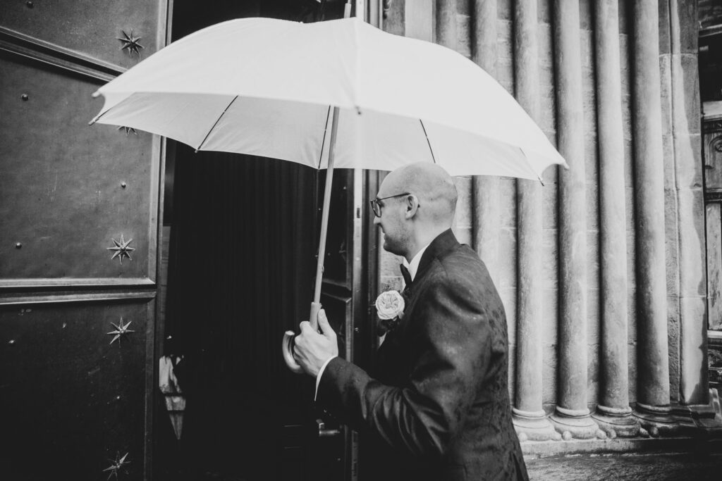 Bräutigam mit Regenschirm vor der Kirche - Fotograf Adrian Flütsch