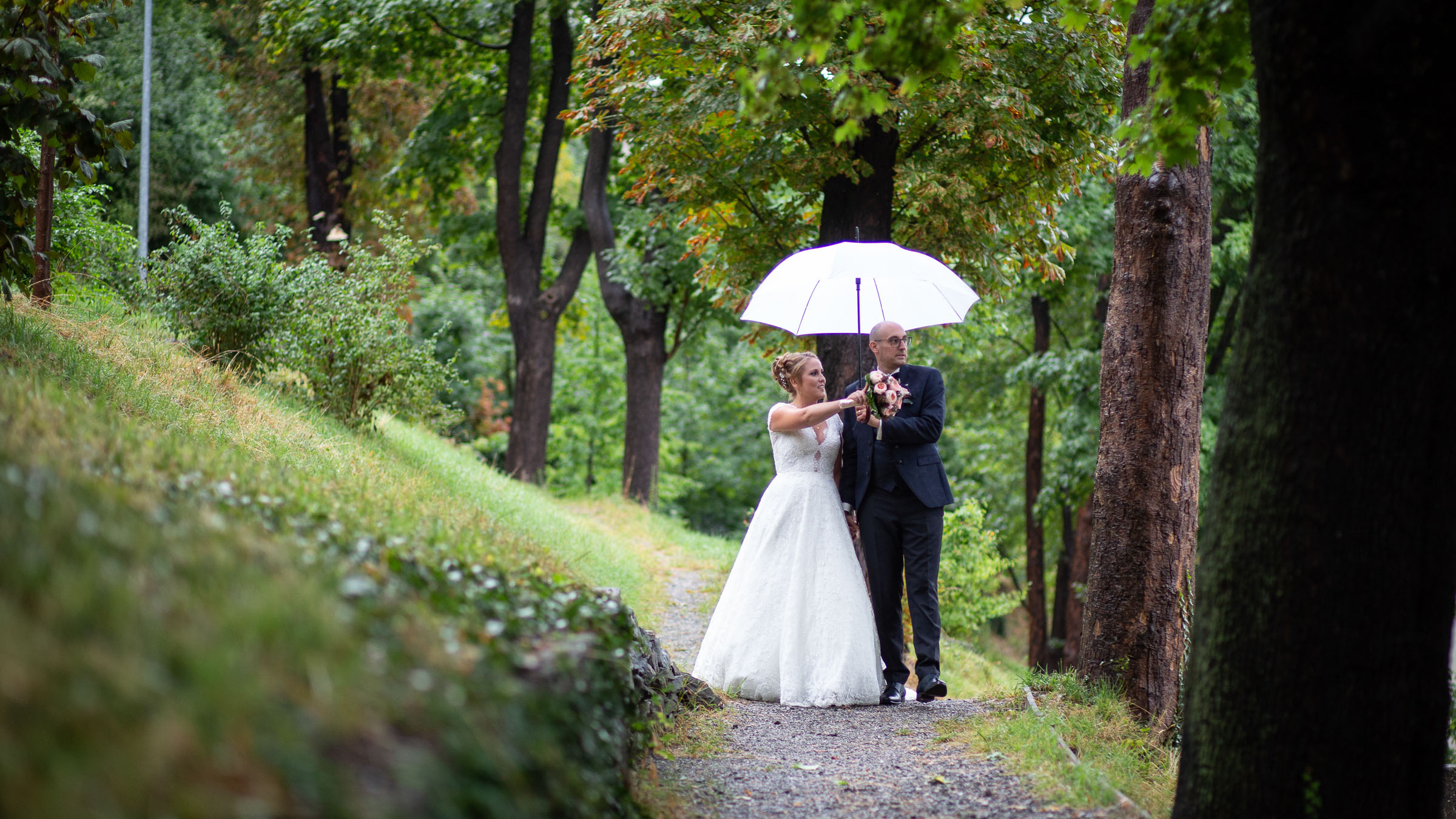 Brautpaar unter einem Regenschirm im Park, fotografiert von Adrian Flütsch.