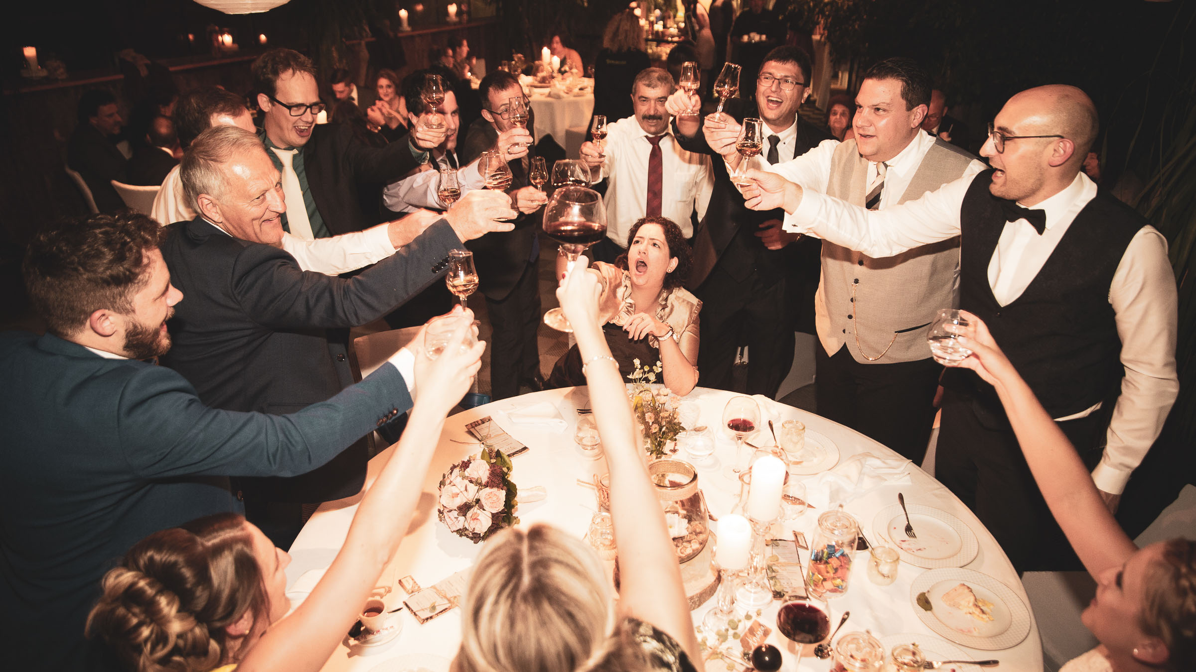 Hochzeitspaar feiert mit Gästen, fotografiert von Adrian Flütsch aus Chur.